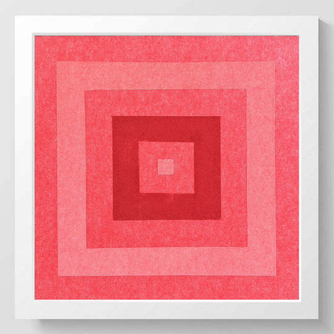 A square framed art print featuring concentric squares in shades of pink and red, with a textured paper finish and a clean white frame.